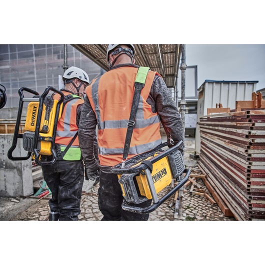 Two construction workers, each carrying a Powershift Powerpack Concrete Vibrator