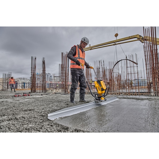 Worker uses Powershift Screed with L shaped beam to screed concrete on construction site