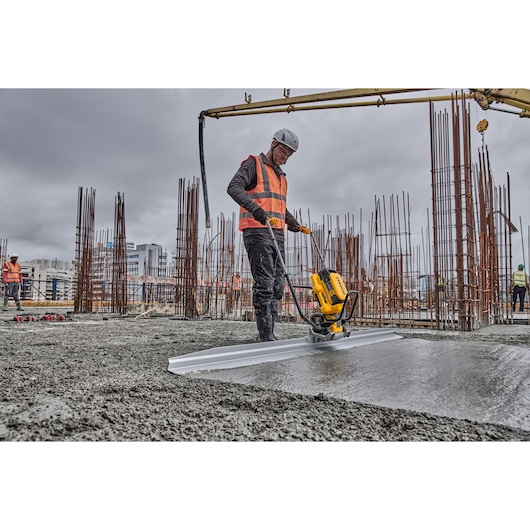 Worker uses Powershift Screed with L shaped beam to screed concrete on construction site