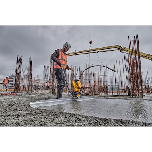 Worker uses Powershift Screed with L shaped beam to screed concrete on construction site