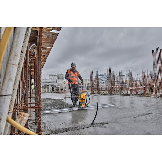 Worker uses Powershift Screed with L shaped beam to screed concrete on construction site