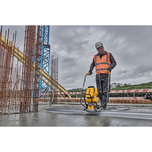 Worker uses Powershift Screed with L shaped beam to screed concrete on construction site