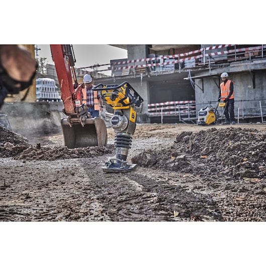 Powershift Rammer on a construction site. A digger bucket and construction workers are in the background