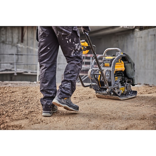 Cropped view of a construction worker using Powershift Plate Compactor. Worker's legs and compactor are in view.