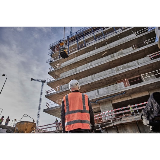 Worker watches a Powershift Plate Compactor being winched into the air on a construction site