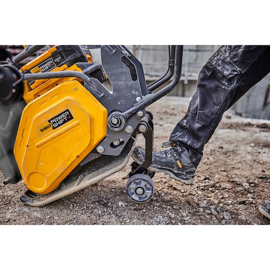 Worker pushes transportation wheels into place on a Powershift Plate Compactor