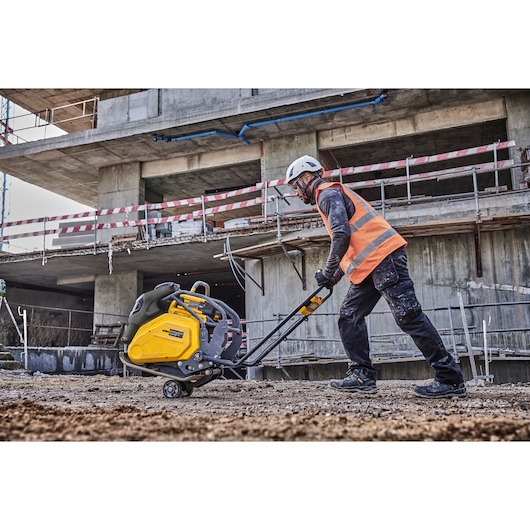 Worker transports Powershift Plate Compactor across a construction site