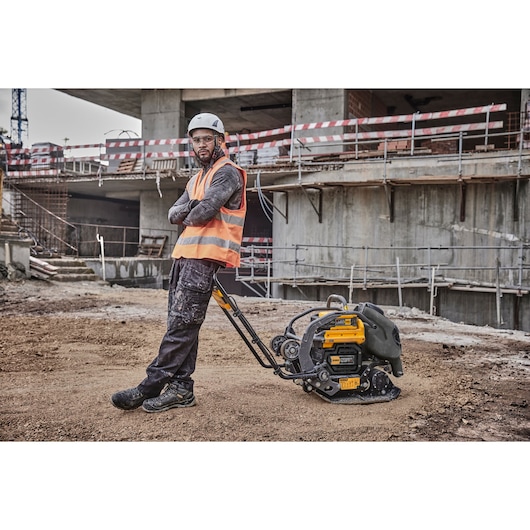 Worker leans against a Powershift Plate Compactor on a construction site