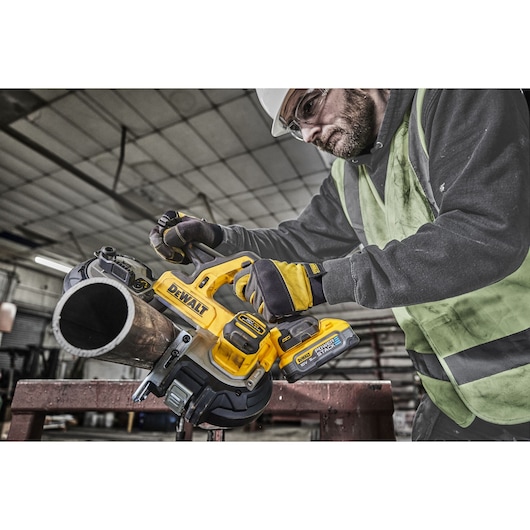 Worker using 18V XR Band Saw to cut metal pipe