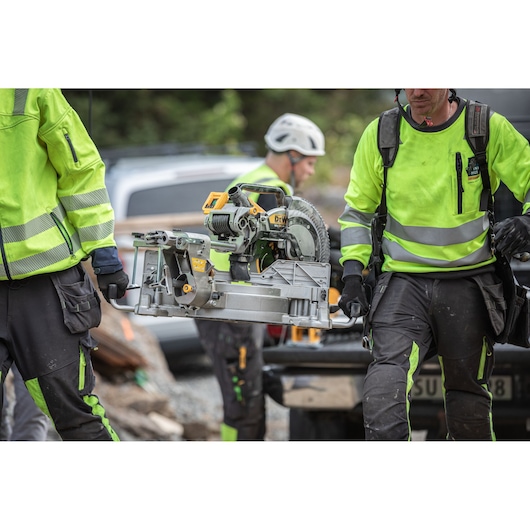 The DEWALT 18V XR 305mm Slide Mitre Saw being carried by workers from truck
