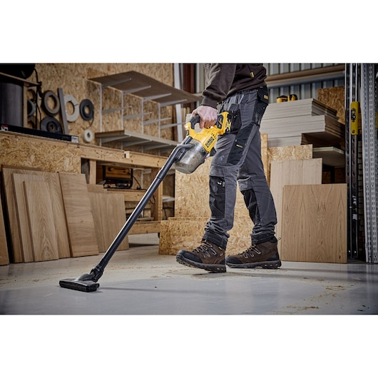 A CARPENTER USING A DCV501L 18V XR L-CLASS STICK VAC TO CLEAN THEIR WORK SHOP FLOOR