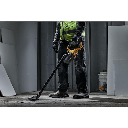 A TRADESMAN USING A DCV501L 18V XR L-CLASS STICK VAC TO CLEAN A SITE FLOOR