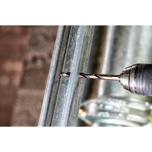 Black and gold metal drill Bit being used to drill through a metal rod.