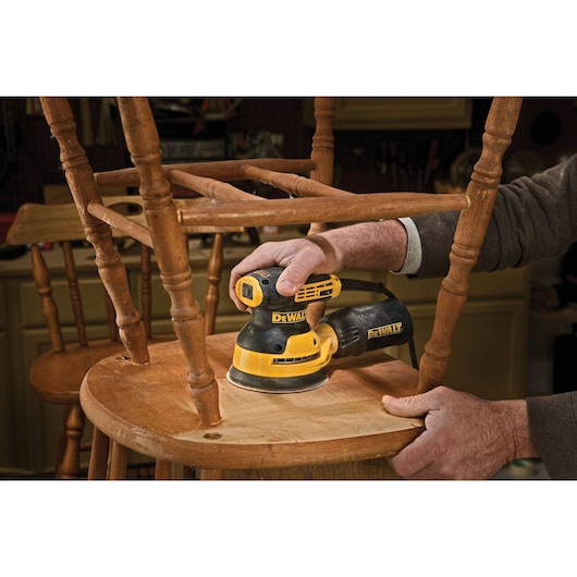 5 inch variable speed random orbit sander sanding bottom of a chair.