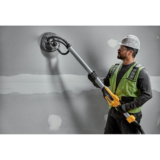 Electric drywall sander polishing wall.
