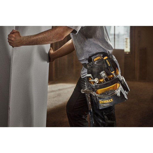 Person wearing the Dewalt Professional tool pouch. The pockets are filled with nails and hand tools.