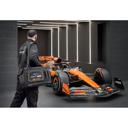 DEWALT/McLaren Tool Bag being carried by a McLaren mechanic walking towards a McLaren racing car