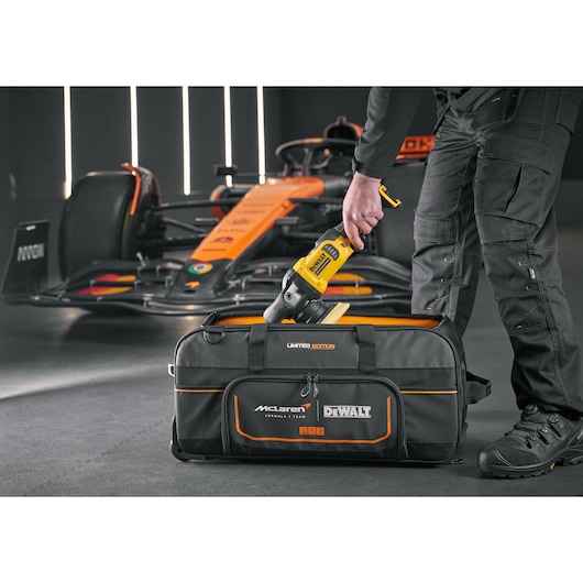 DEWALT tool being placed into a DEWALT/McLaren Duffle Bag DEWALT/McLaren Duffle Bag with wheels